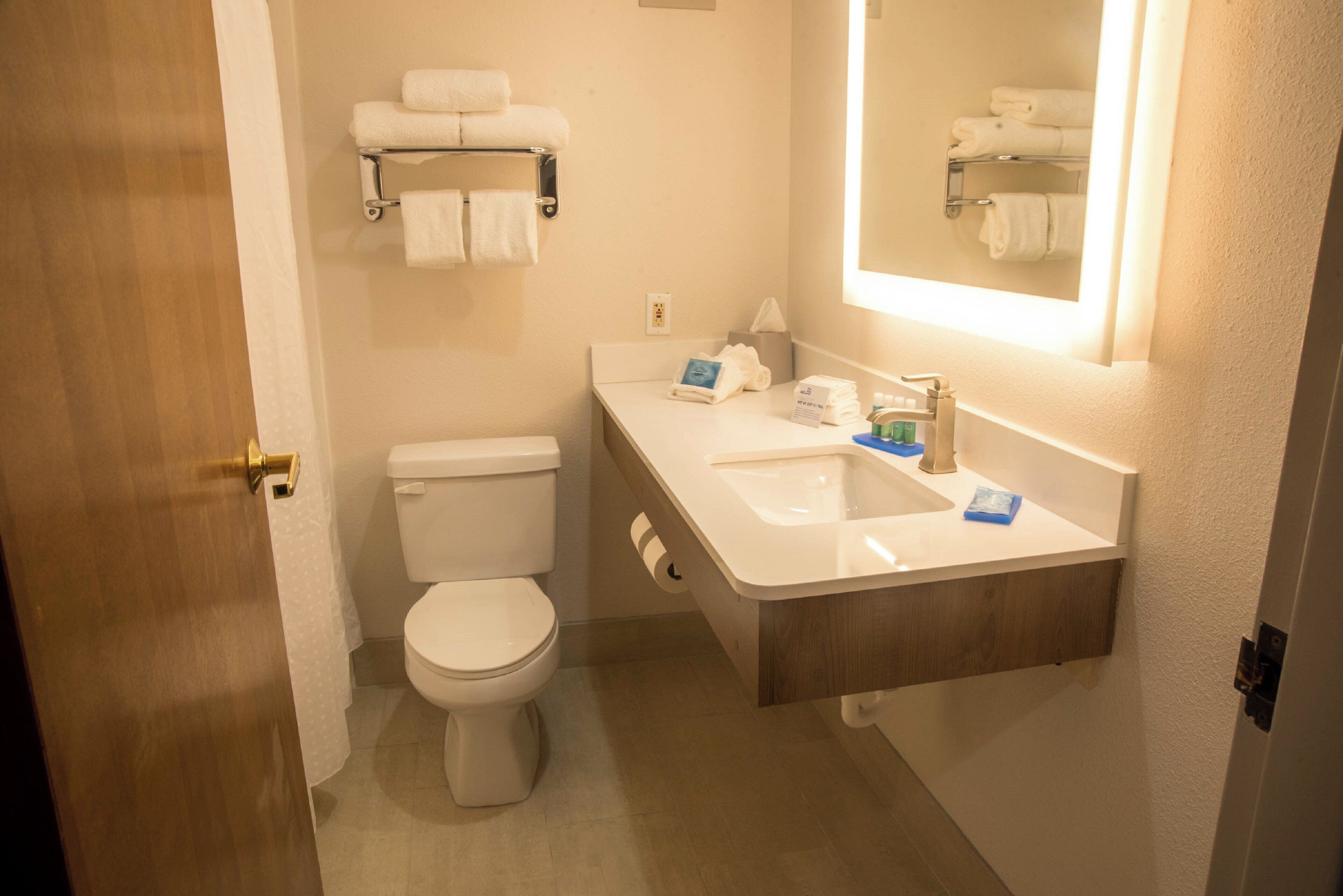 Un baño con inodoro, lavamanos, espejo y toallero.