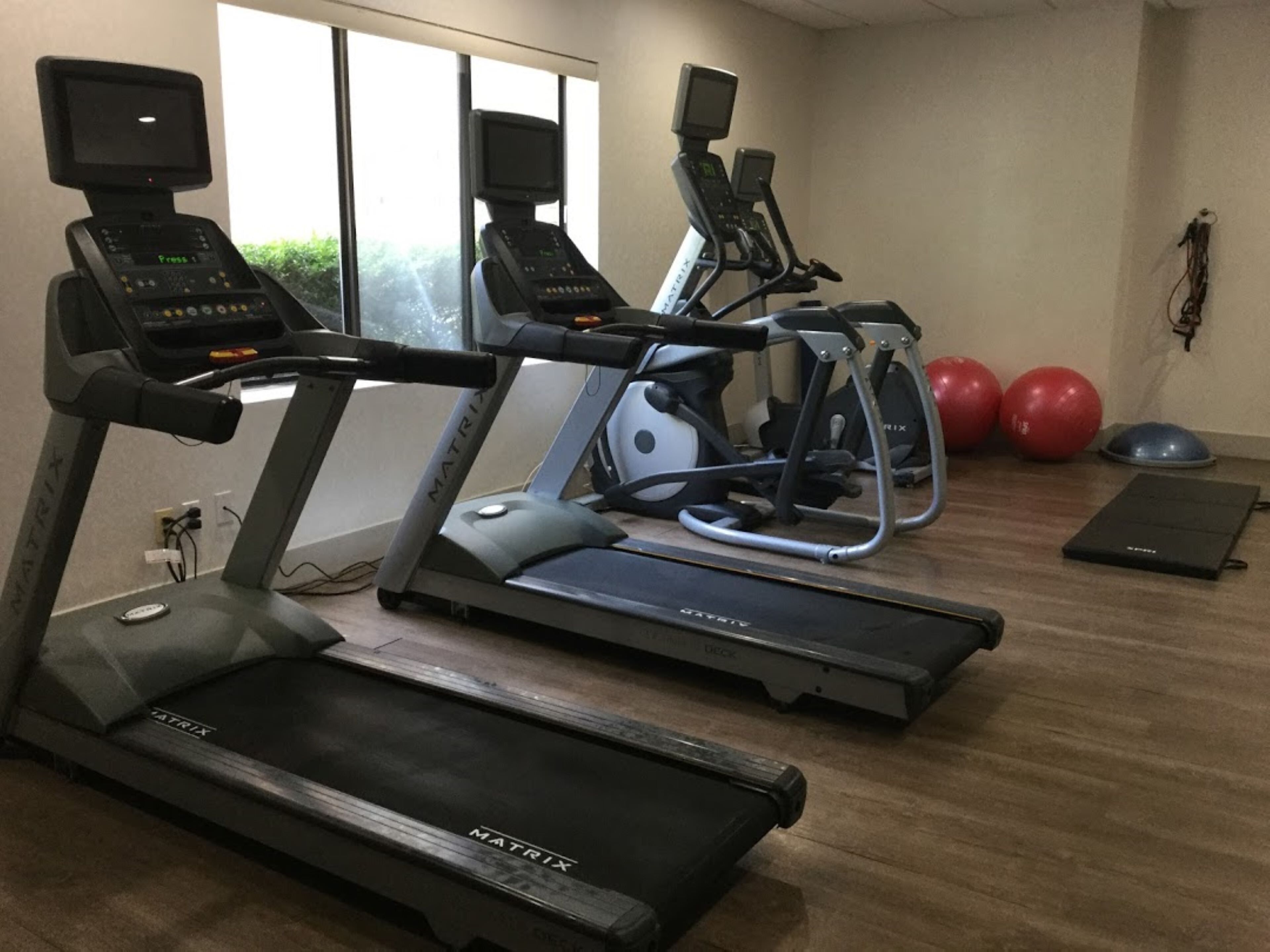 Un gimnasio con cintas de correr, elípticas y pelotas de ejercicio.