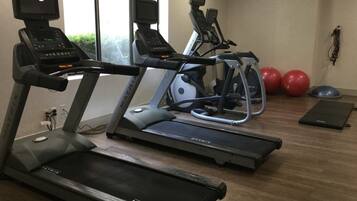 Un gimnasio con cintas de correr, elípticas y pelotas de ejercicio.