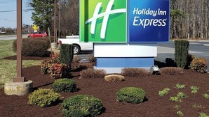 A Holiday Inn Express sign with a green and blue logo, surrounded by landscaped garden beds and trimmed hedges. - Holiday Inn Express Easton by IHG (Easton)