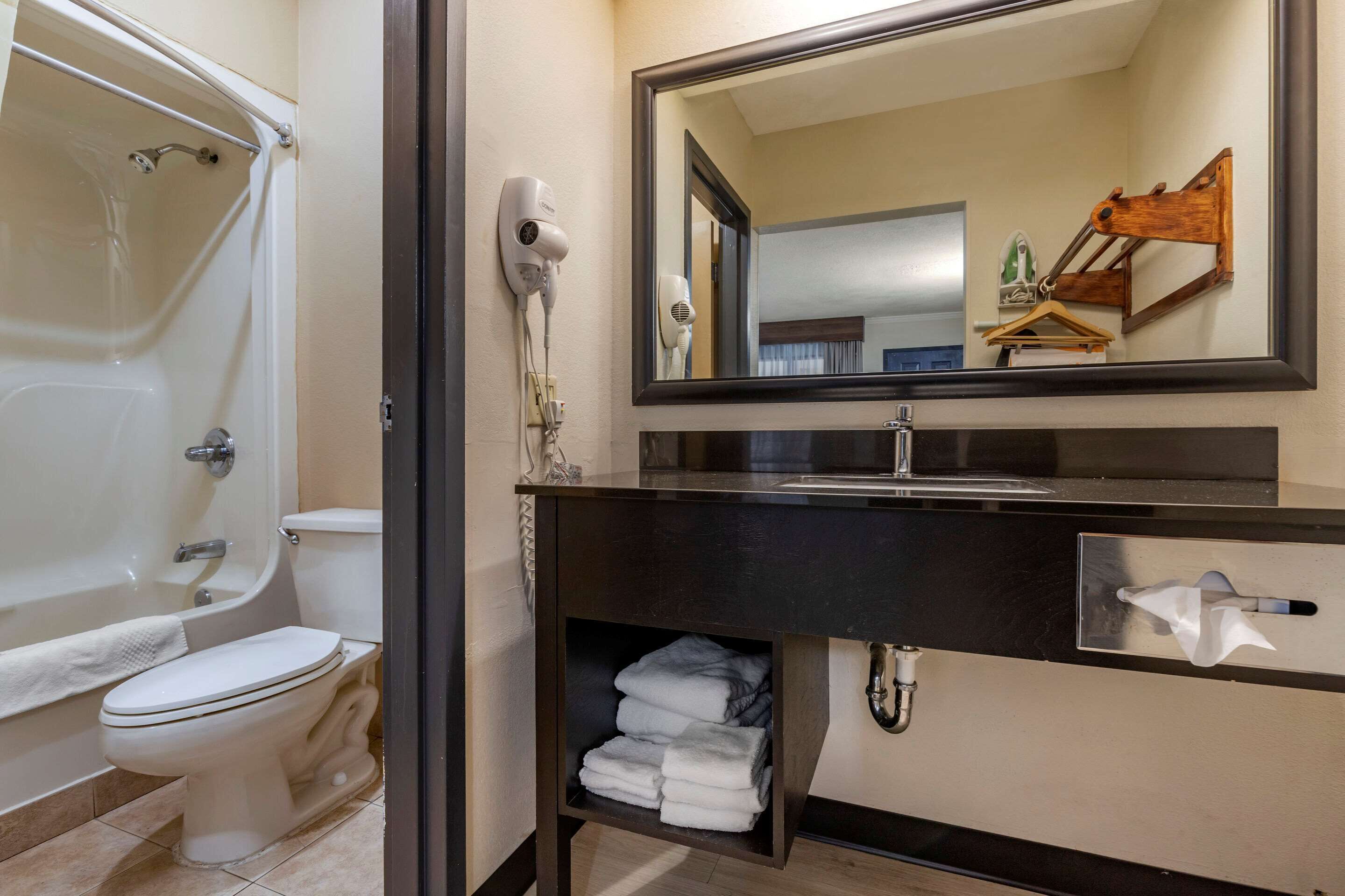 A bathroom with a bathtub, toilet, and a vanity with a mirror.