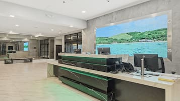 A reception desk with a large window displaying a coastal landscape, a modern interior with a marble floor, and a reception area with a counter and seating.