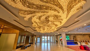 A spacious lobby with a large chandelier, marble flooring, and a reception area with seating. - Grand Tuscany Hotel (Houston)