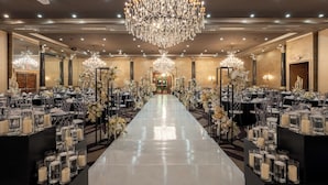 A banquet hall with a long table, chandeliers, and floral arrangements. - Grand Tuscany Hotel (Houston)