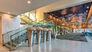 A grand lobby with a marble floor, a glass staircase, and a ceiling with a starry sky design. - Grand Tuscany Hotel (Houston)