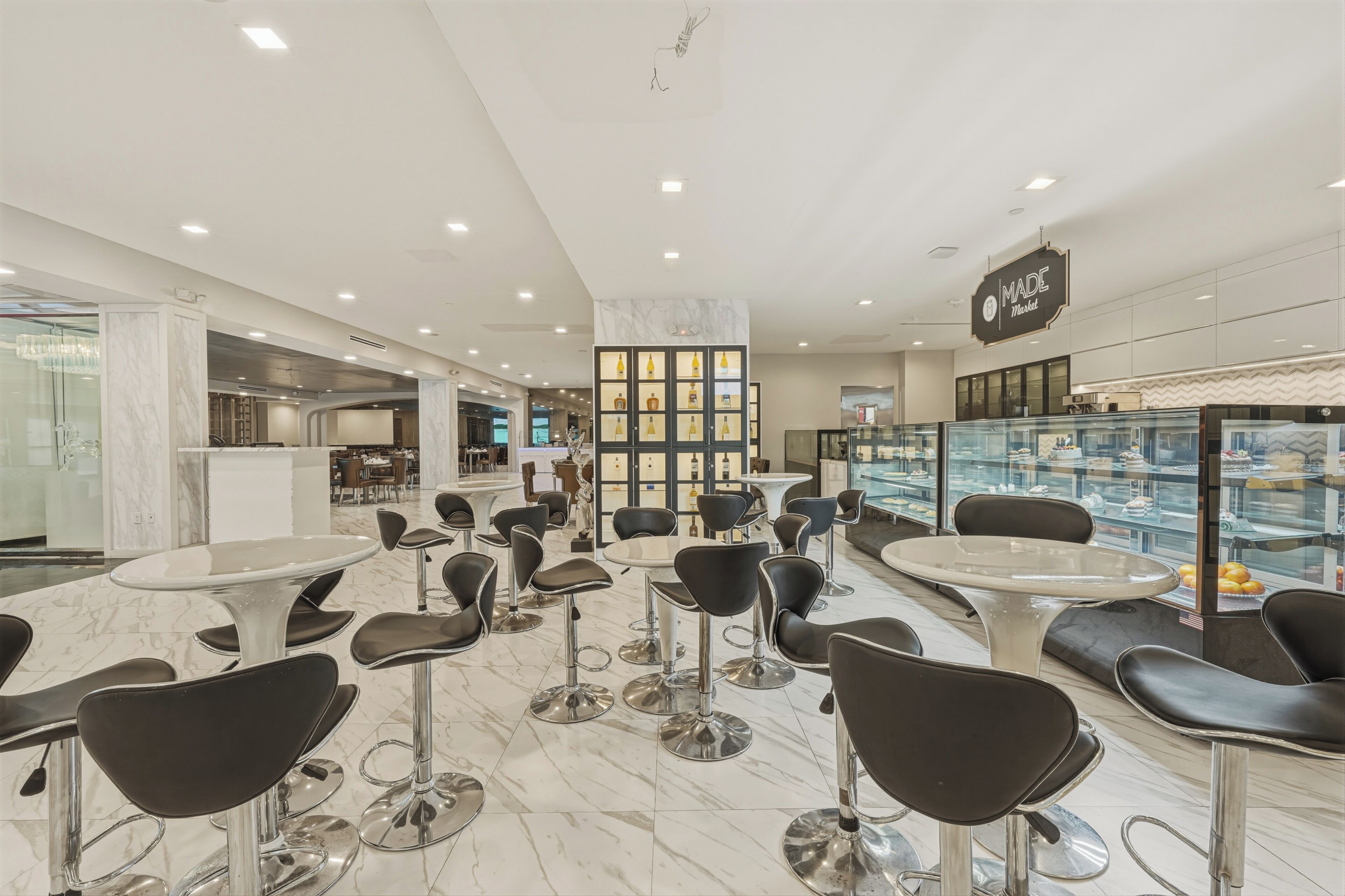 Un interior moderno con asientos de bar, suelo de mármol y una vitrina con objetos.