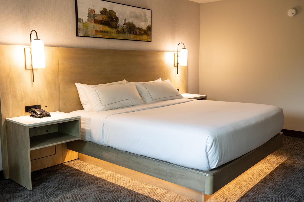 A hotel room with a bed, bedside tables, a telephone, and wall-mounted lamps.
