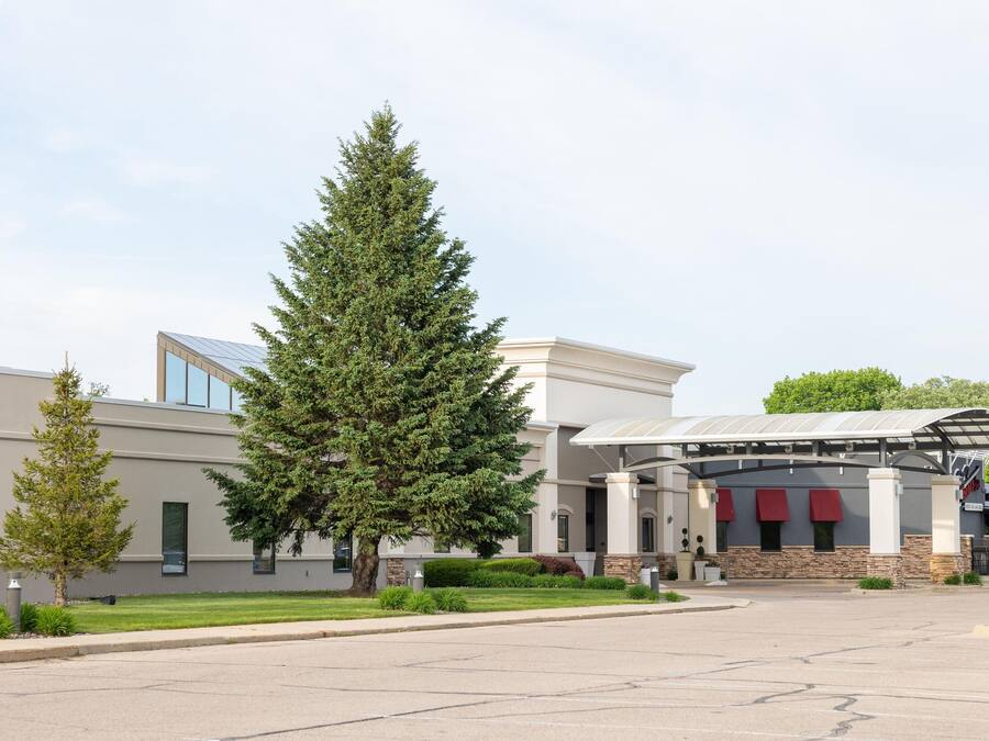 A modern building with a covered entrance, large windows, and a parking lot.