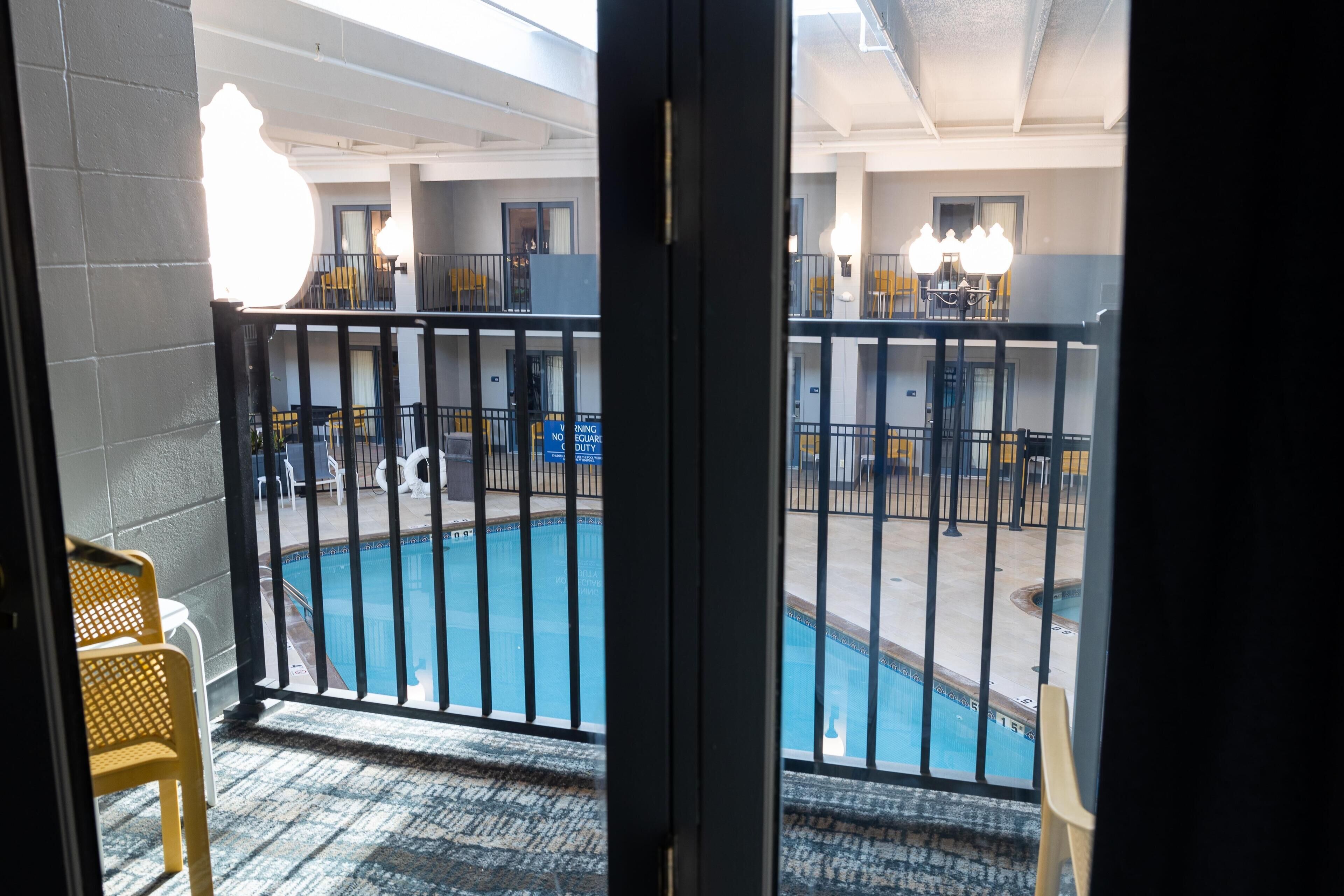 Vista de una piscina con un balcón, una silla y un cartel que indica su ubicación.