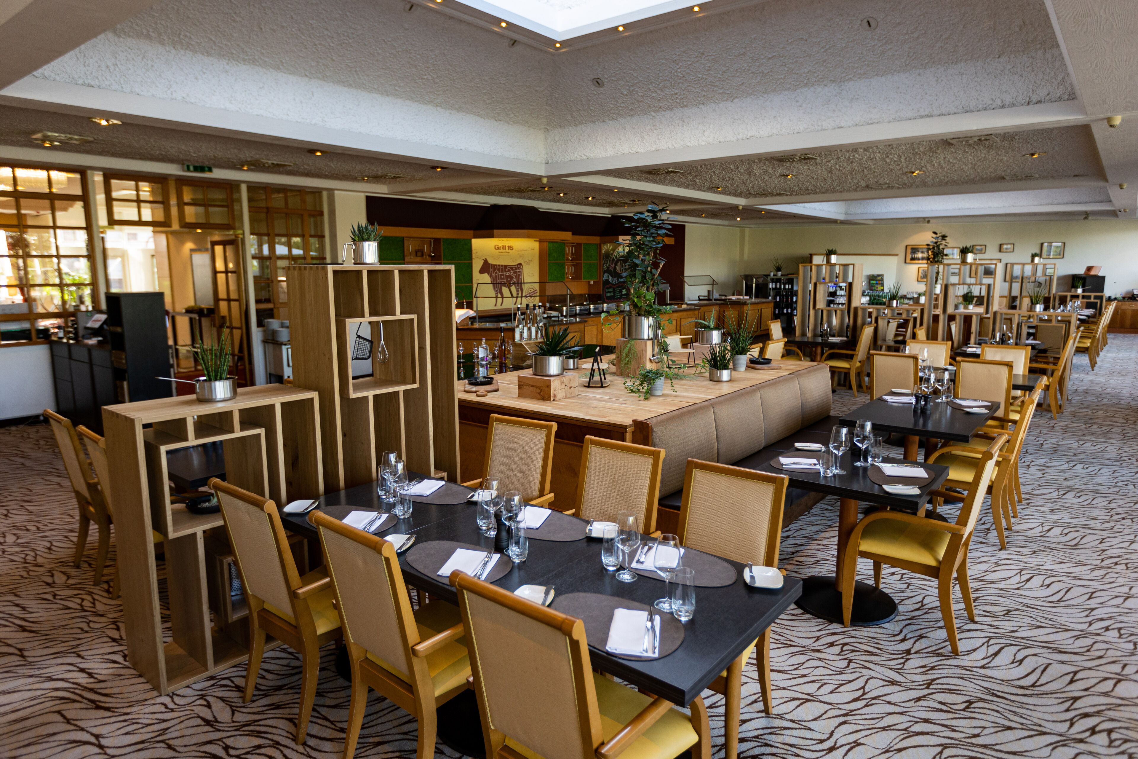 A spacious restaurant with multiple dining areas, including a central booth and several tables with chairs.