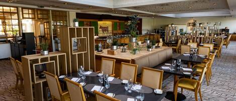 A spacious restaurant with multiple dining areas, including a central booth and several tables with chairs.