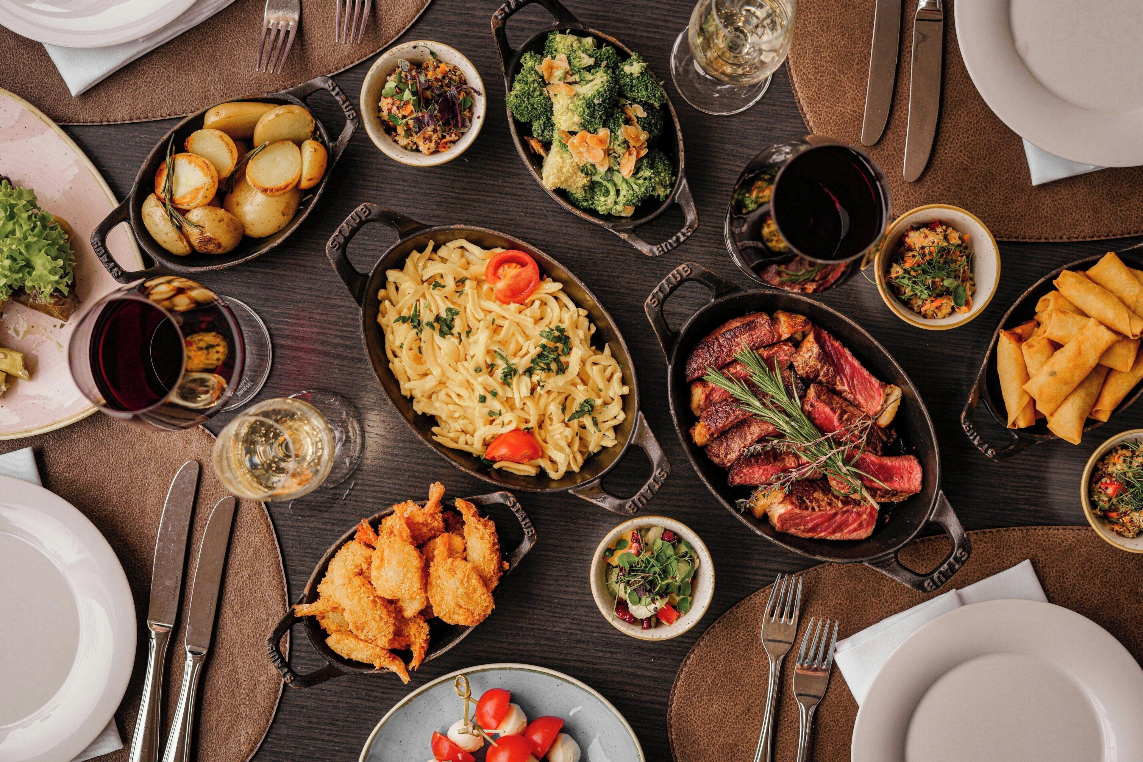 A dining table with various dishes including pasta, steak, and fried items.