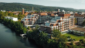 Un hotel de varios pisos, una torre destacada y un río al frente.