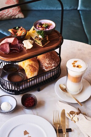 Una mesa con un organizador de niveles para servir, una taza de café y diferentes alimentos.