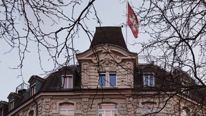 A historic building with a sign reading "AMBASSADOR" and a flag above it. - Small Luxury Hotel Ambassador Zürich (Zürich)