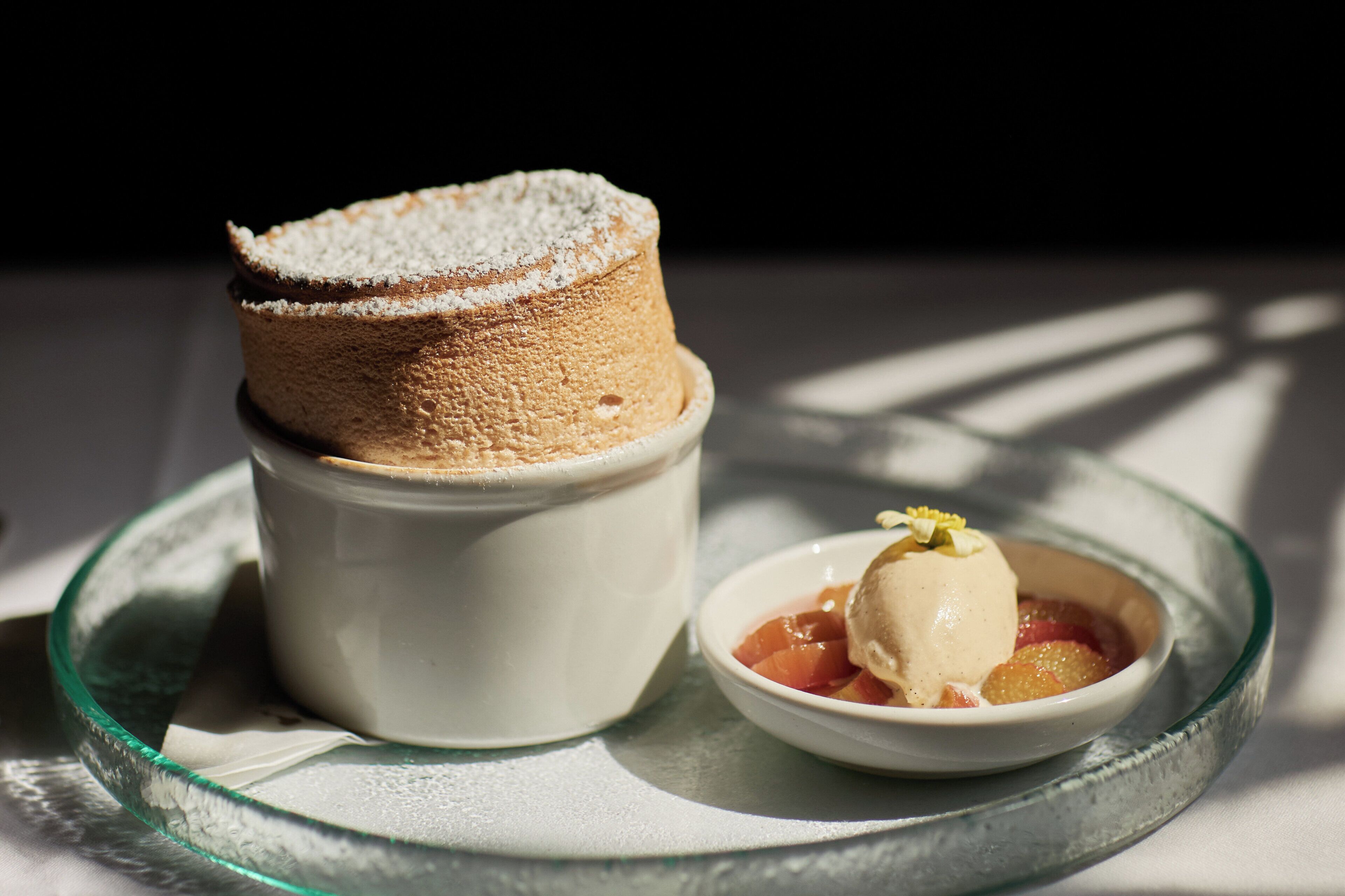 A dessert consisting of a cake and ice cream on a glass plate.