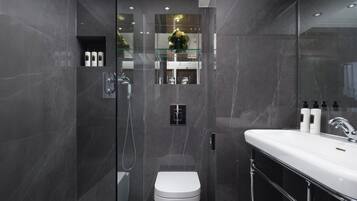Une salle de bain moderne avec une douche à parois de verre, des toilettes blanches et un meuble-lavabo avec un évier et des articles de toilette.