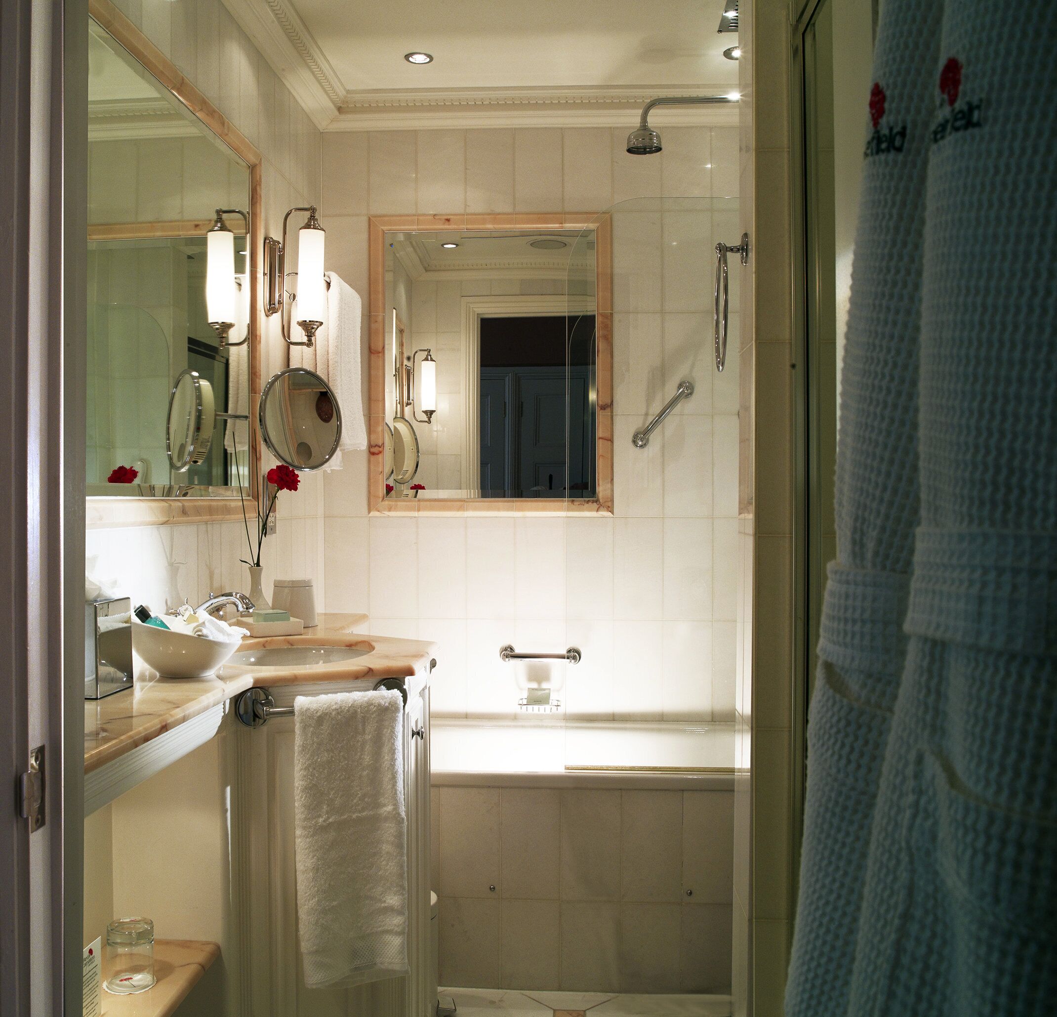 A bathroom with a large mirror, two sinks, a bathtub, and a shower.