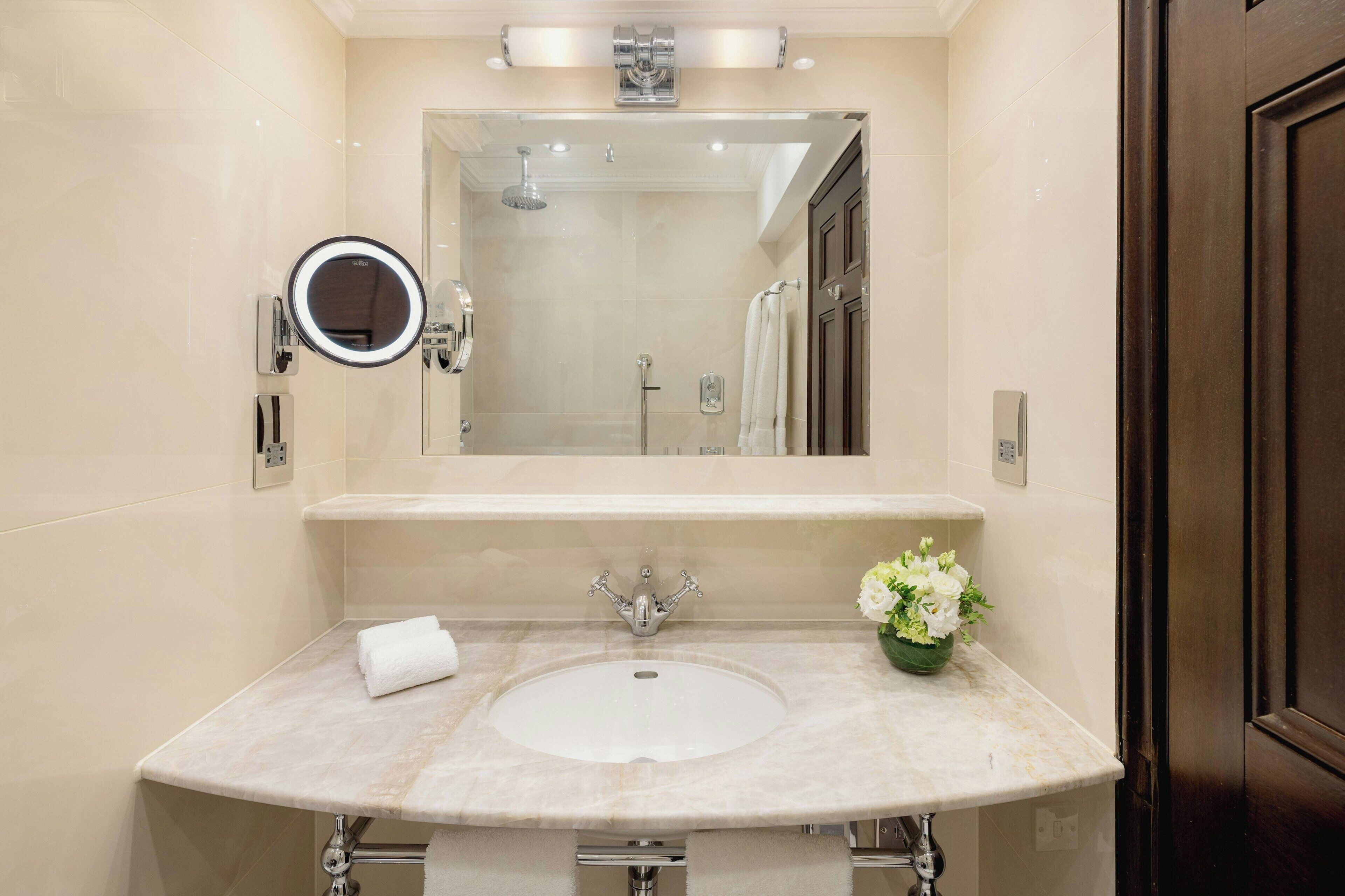 A bathroom with a large mirror, a sink, and a shower.