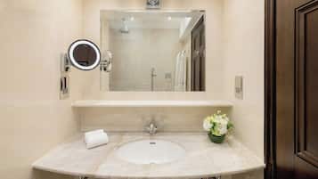 A bathroom with a large mirror, a sink, and a shower.