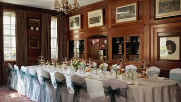 Comedor formal con una larga mesa dispuesta para una comida, paredes con paneles de madera y cuadros enmarcados.