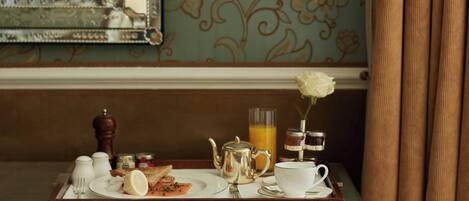 Un plateau de petit-déjeuner avec des toasts, un citron, une théière, une tasse et un verre de jus d’orange, posé sur une table en bois.