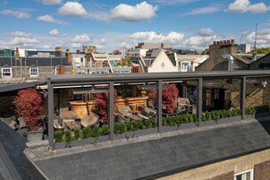 Eine Dachterrasse mit Sitzgelegenheiten im Freien und Blick auf die Skyline.
