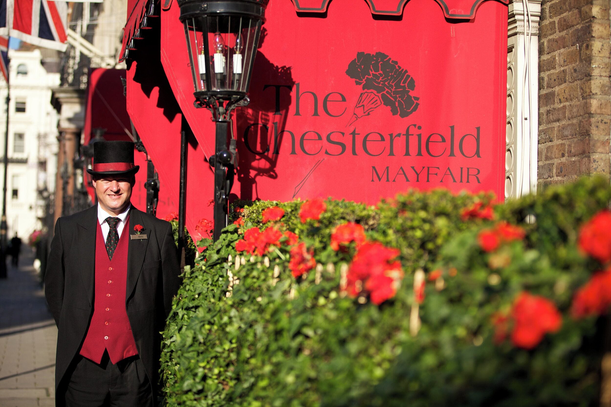 A uniformed staff member standing in front of a red sign with the text 'The Chesterfield Mayfair.'