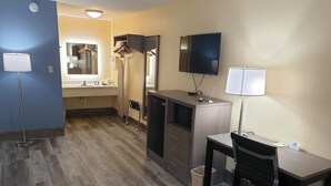 A hotel room with a desk, chair, TV, and a mirror. - Days Inn by Wyndham Cleveland TN (Cleveland)
