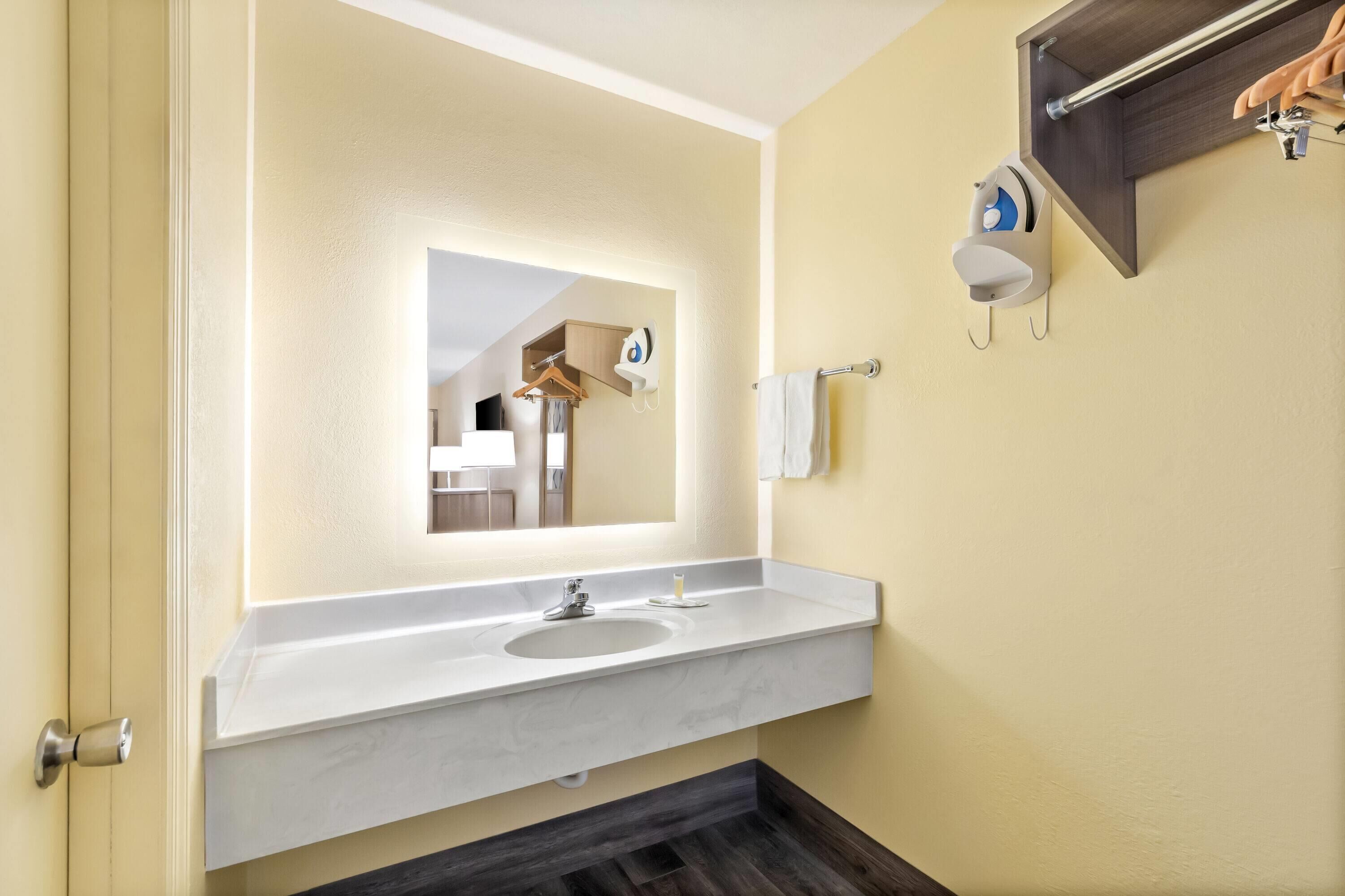 A bathroom with a white sink, a mirror, a towel rack, and a hanging towel.