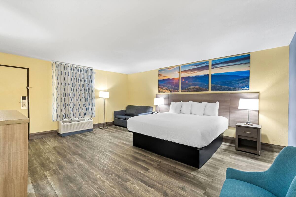 A hotel room with a large bed, a sofa, a desk, and a nightstand.