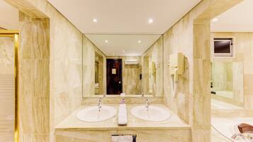 A modern bathroom with two sinks, a large mirror, and a shower area.