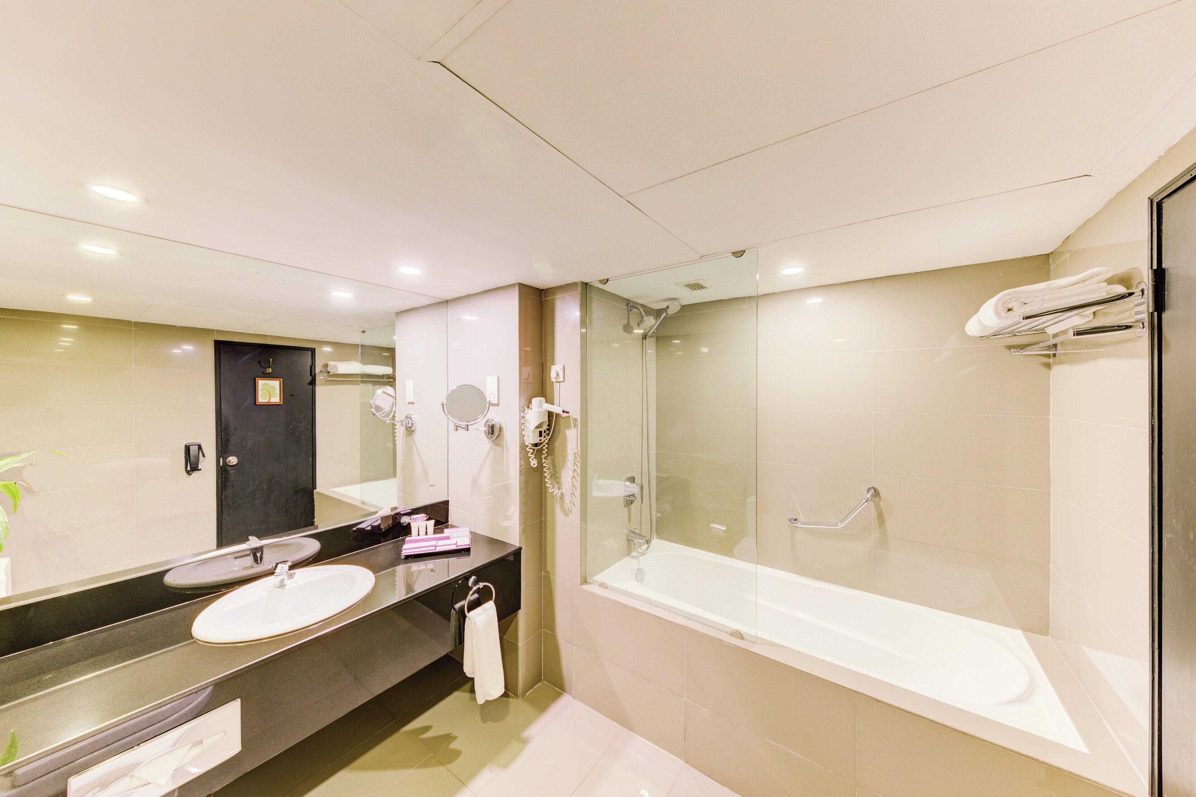 Une salle de bain moderne avec un grand miroir, un lavabo, une baignoire et une douche à parois de verre.