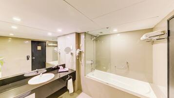 Une salle de bain moderne avec un grand miroir, un lavabo, une baignoire et une douche à parois de verre.