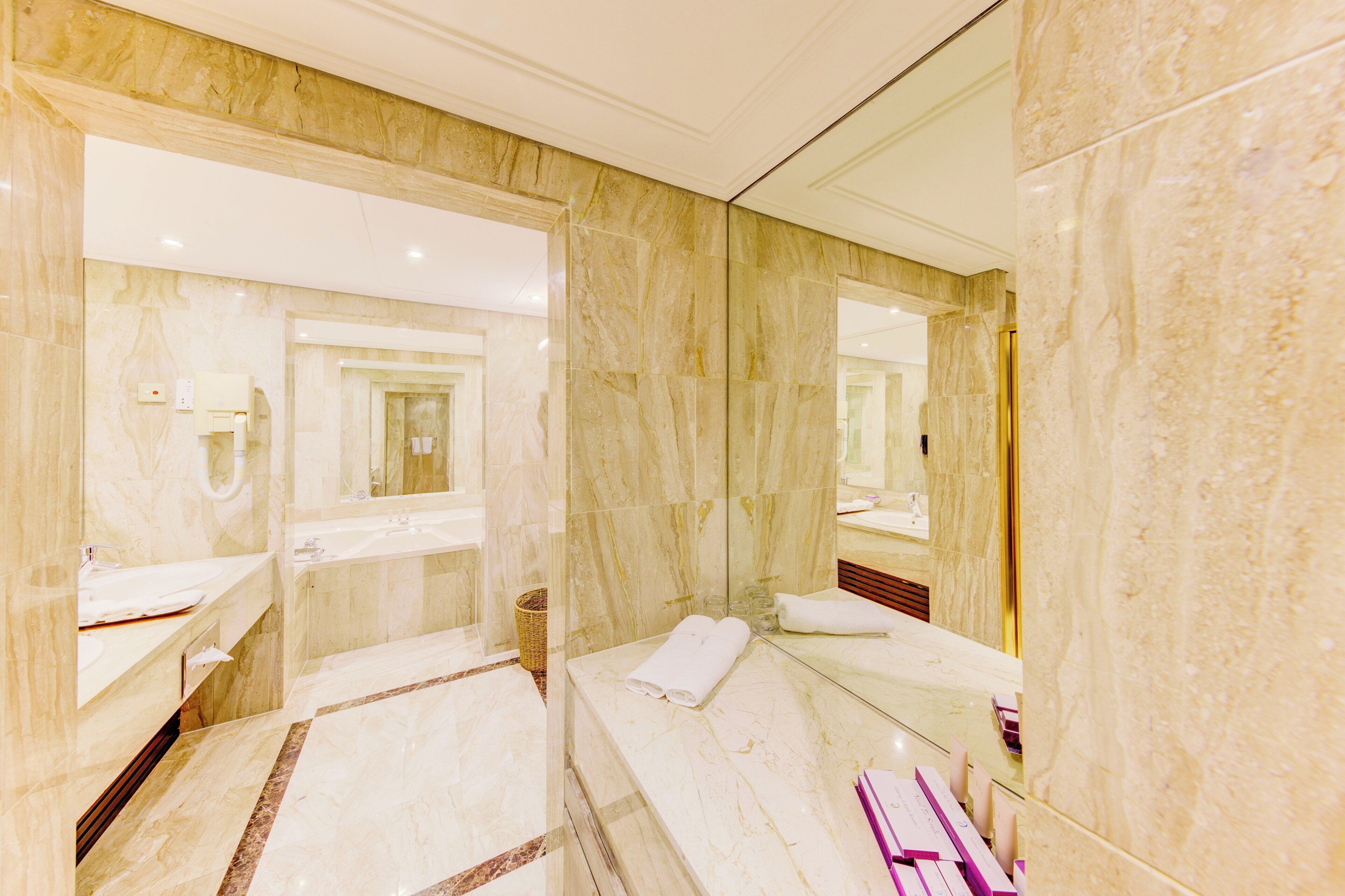Un baño moderno con paredes de mármol y un espejo grande.