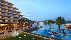 Een hotel met een zwembad, terras en uitzicht op het water.