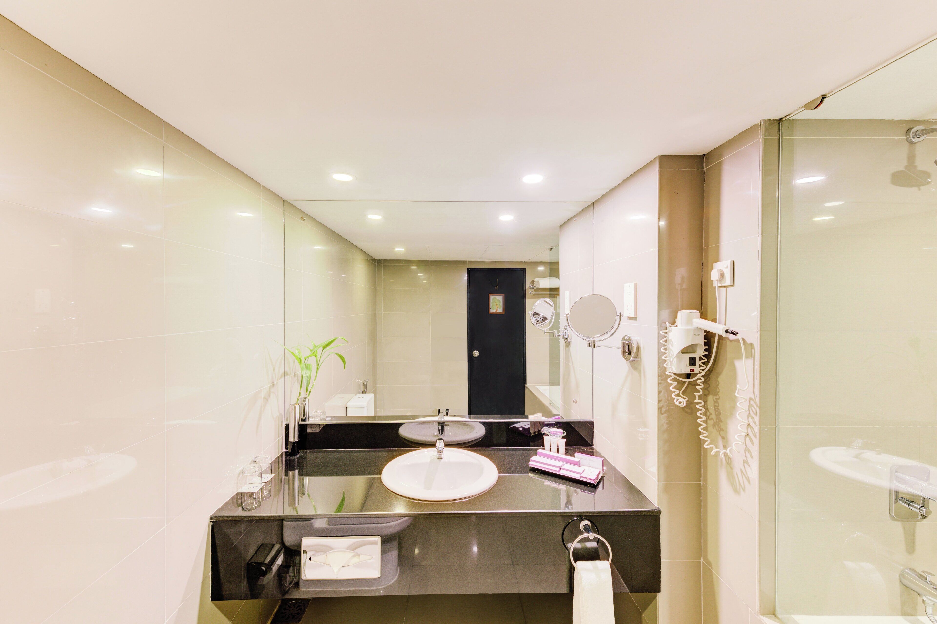 Un baño moderno con un espejo grande, un lavabo redondo y una ducha con cerramiento de vidrio.