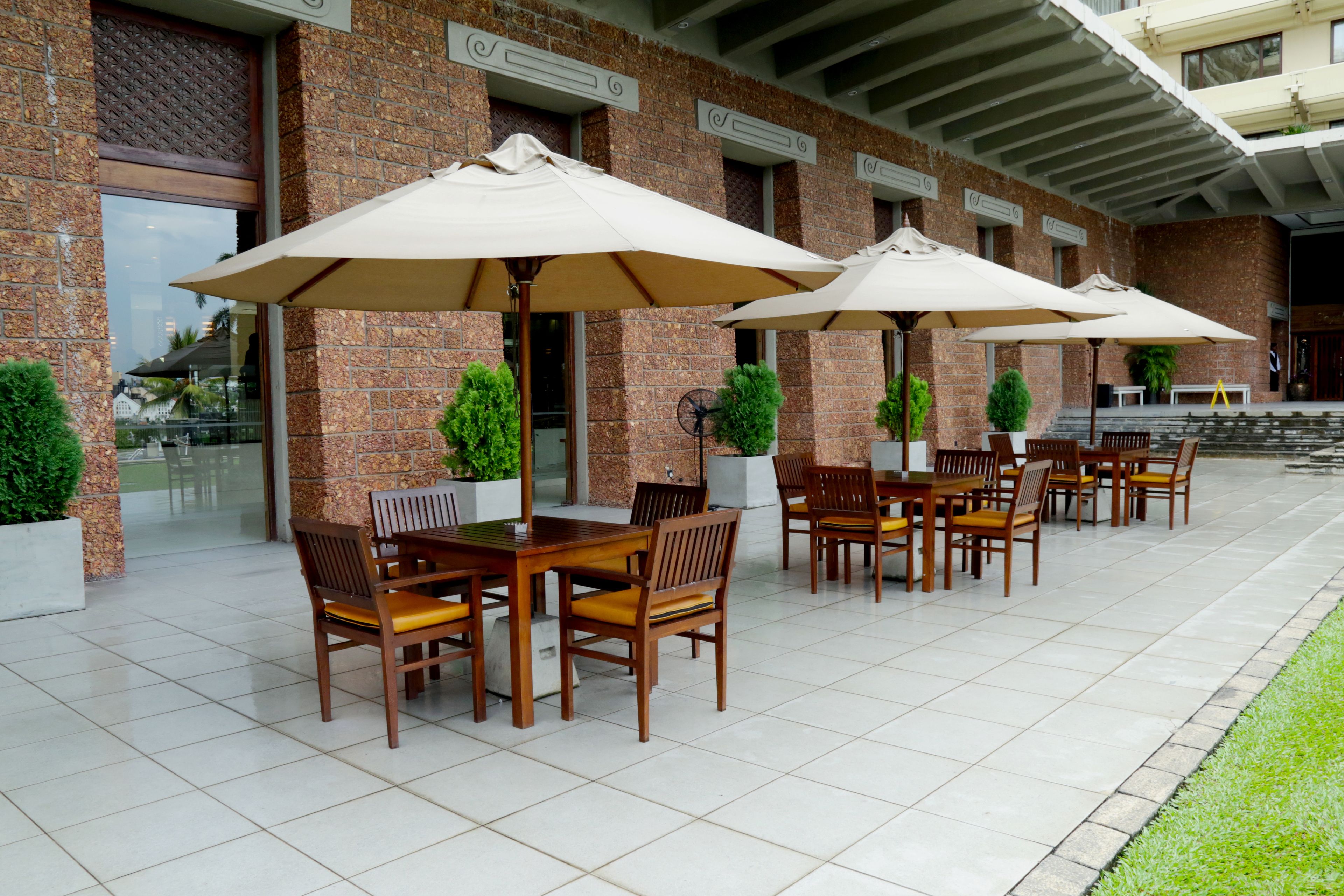 An outdoor patio with brick walls, tiled flooring, and wooden tables and chairs.
