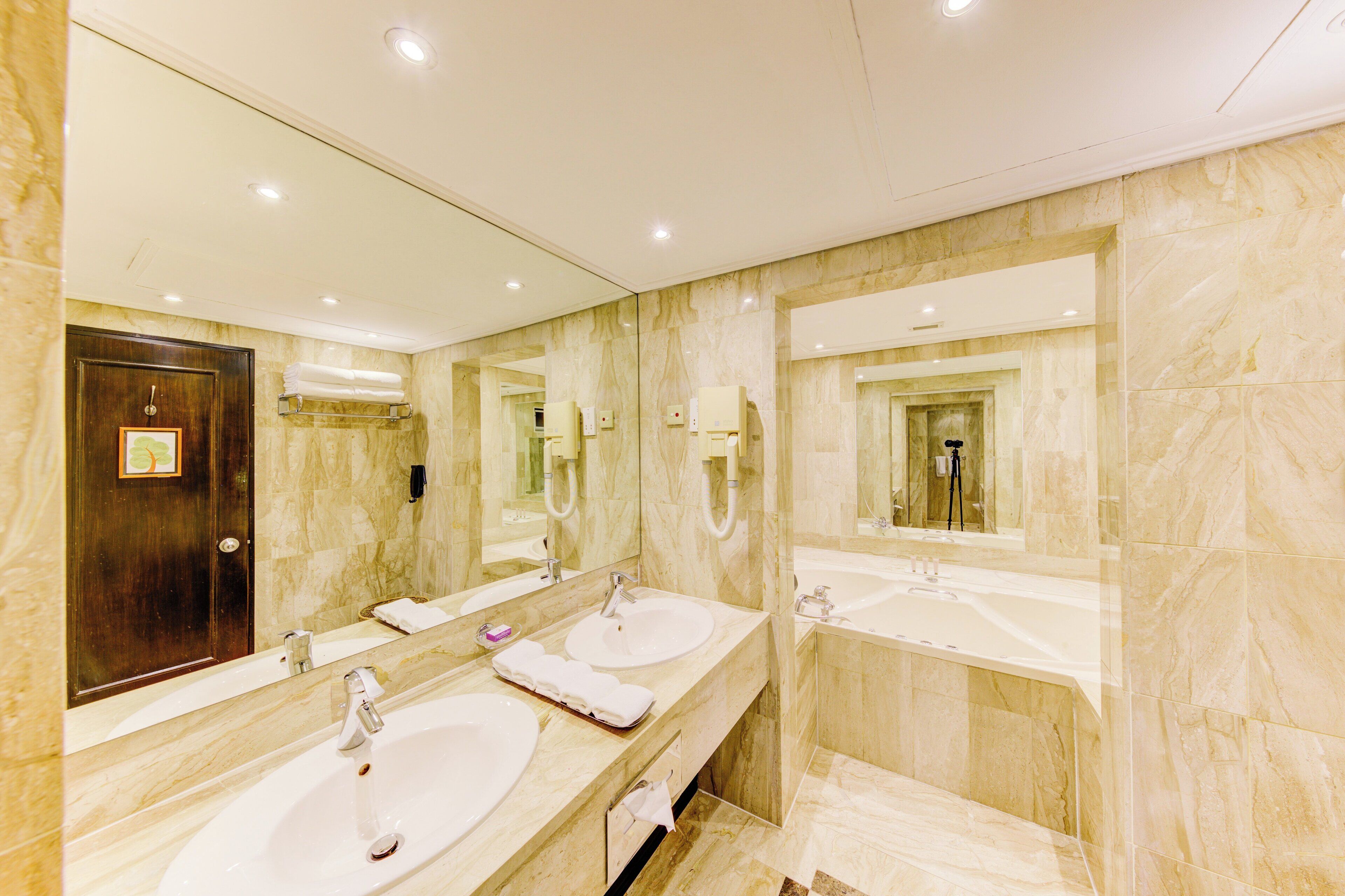 A modern bathroom with two sinks, marble walls, and a large mirror.