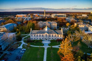 A large institutional building with a central clock tower, surrounded by a well-maintained lawn and parking area. - Holiday Inn South Kingstown (Newport Area) by IHG (Saunderstown)