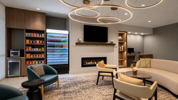 A modern living room with a fireplace, seating area, and a beverage refrigerator.