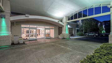 L’entrée d’un hôtel, avec un passage couvert, des portes en verre et un espace de stationnement.