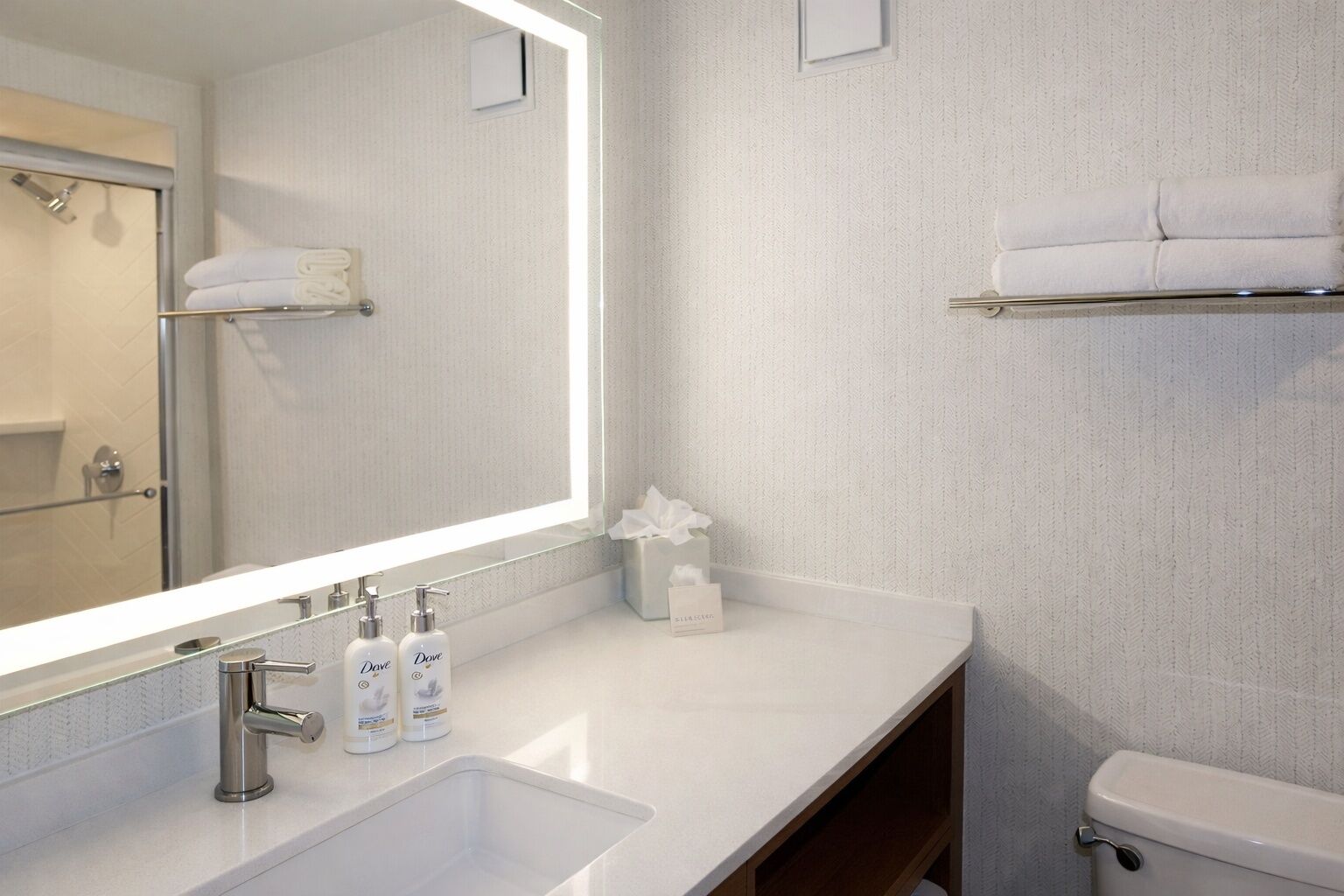 Un baño moderno con un espejo grande, un lavamanos y un inodoro.