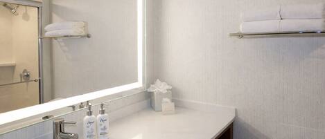 A modern bathroom with a large mirror, a sink, and a toilet.