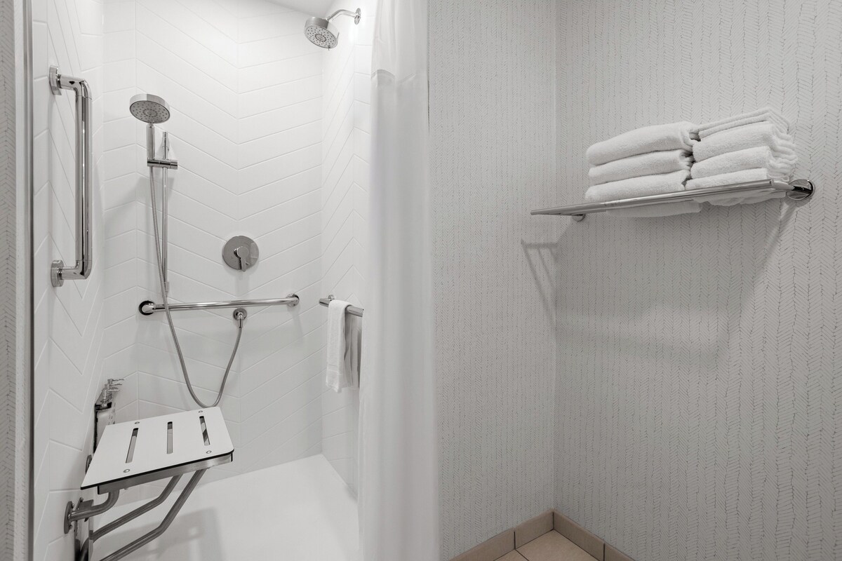 Une douche équipée d’un pommeau de douche à main, d’un flexible de douche et d’un robinet mural.