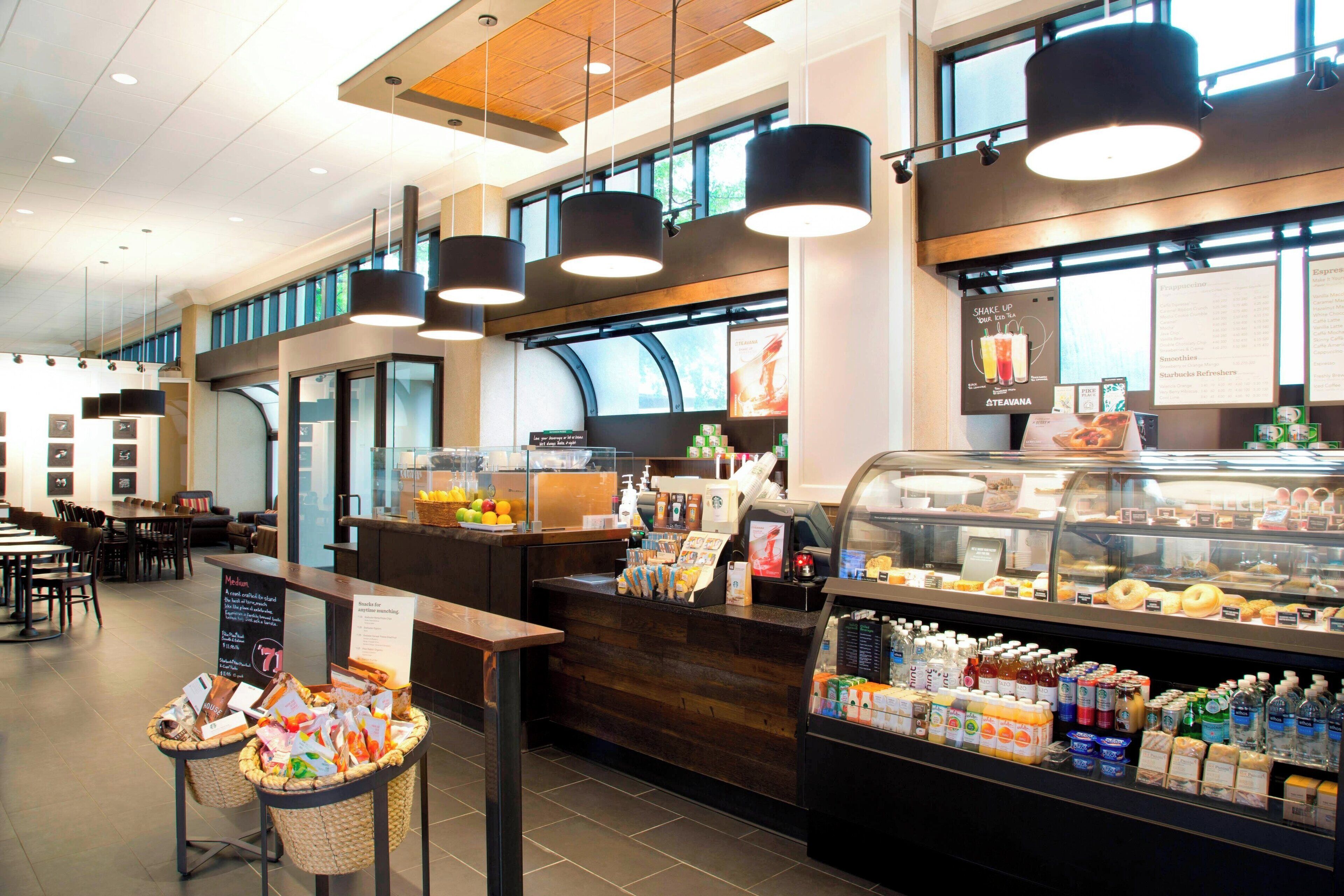 A modern cafe with a wooden counter, a display case with pastries, and baskets of snacks.