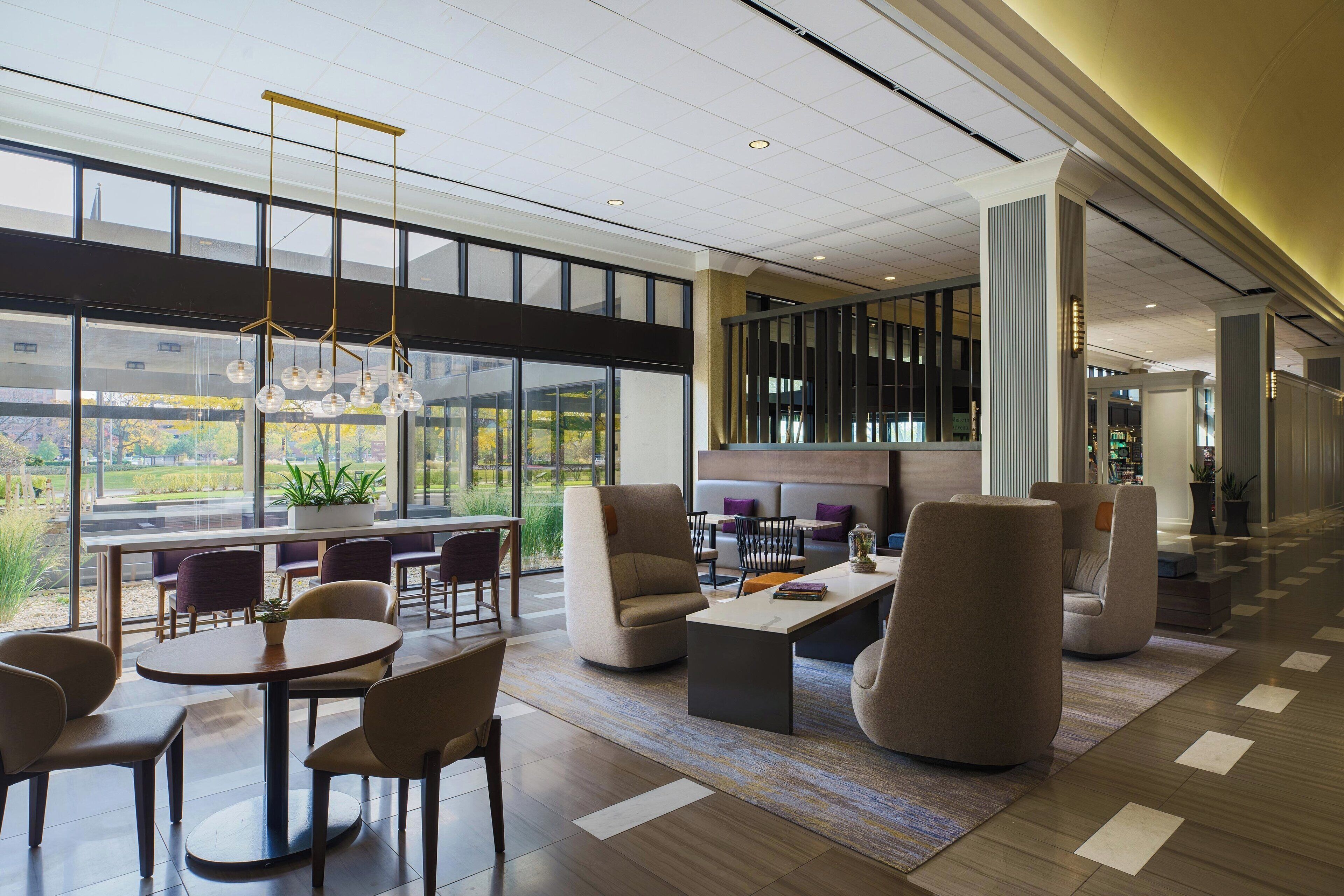 Un hall amplio con mobiliario moderno, ventanas grandes y un techo con diseño de cuadrícula.