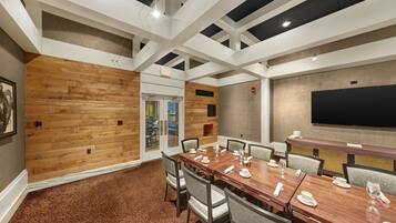 A conference room with a wooden panel wall, a large flat-screen TV, and a carpeted floor.