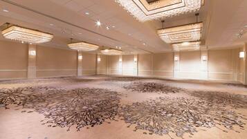 A spacious conference room with ornate chandeliers and a detailed carpet design.