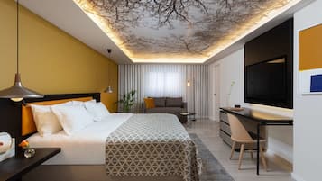 Quarto de hotel moderno com uma cama grande, uma escrivaninha e uma televisão.
